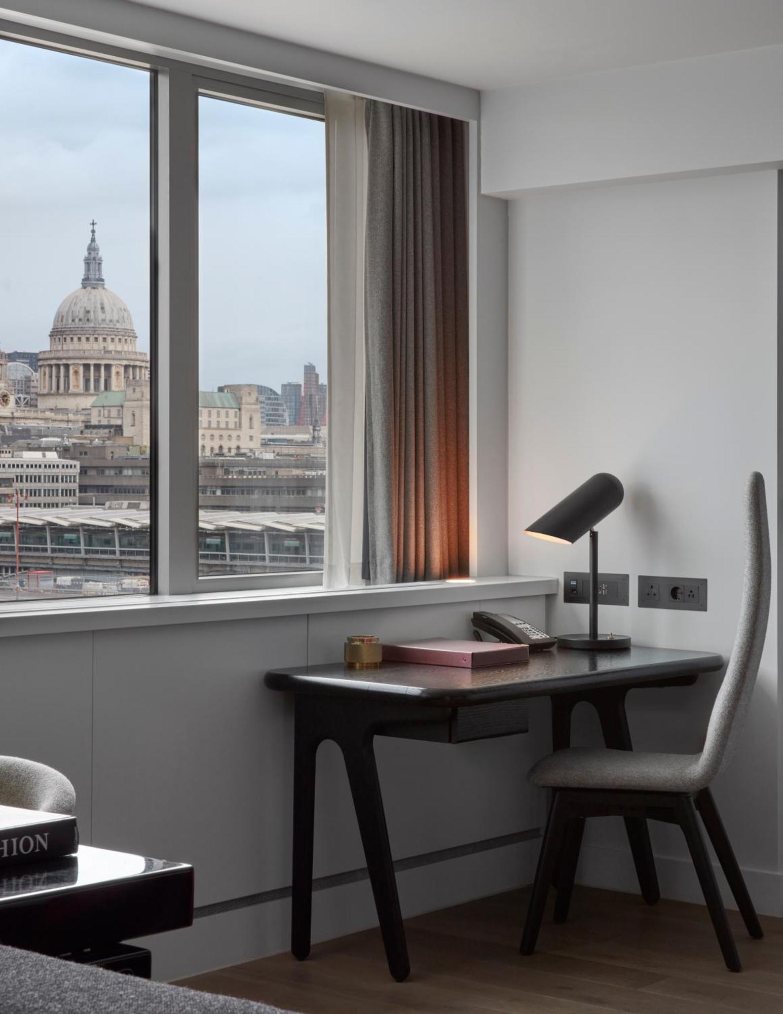 Hotel Sea Containers Londra Esterno foto The photo shows a modern office space with a view of a cityscape featuring a prominent dome, likely a historic building. There's a sleek desk with a lamp, a phone, and some stationery. The room has large windows allowing natural light to enter, and t