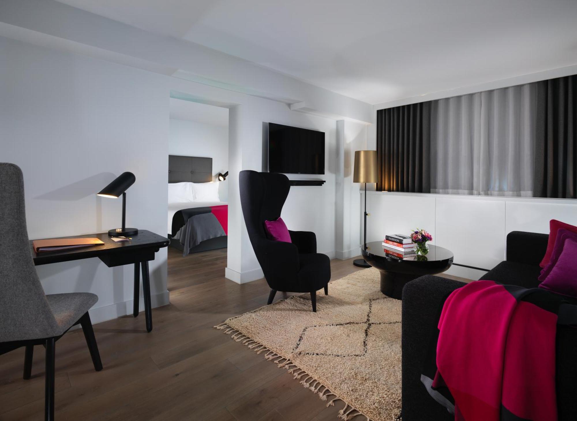Hotel Sea Containers Londra Esterno foto The photo depicts a modern living space, likely part of a hotel room or suite. The room features:

- A comfortable seating area with two stylish armchairs in black, adorned with pink throw pillows.
- A small coffee table in the center, accompanied by