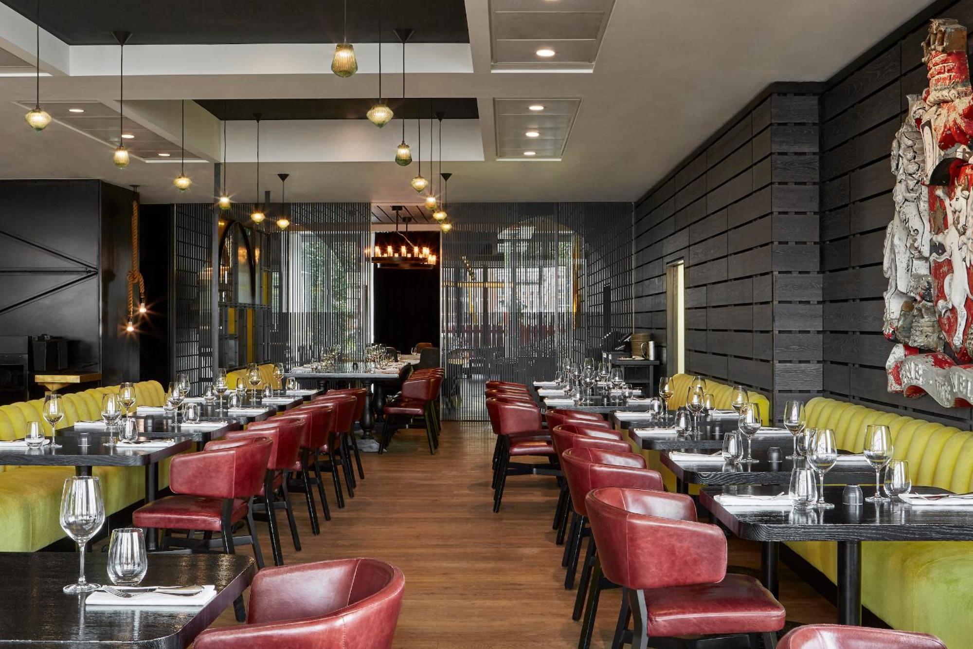 Hotel Sea Containers Londra Esterno foto The photo shows an interior of a modern restaurant. It features a combination of wooden and metallic elements, with a sleek design. The tables are set with cutlery and glassware, indicating readiness for diners. There are red and yellow upholstered c