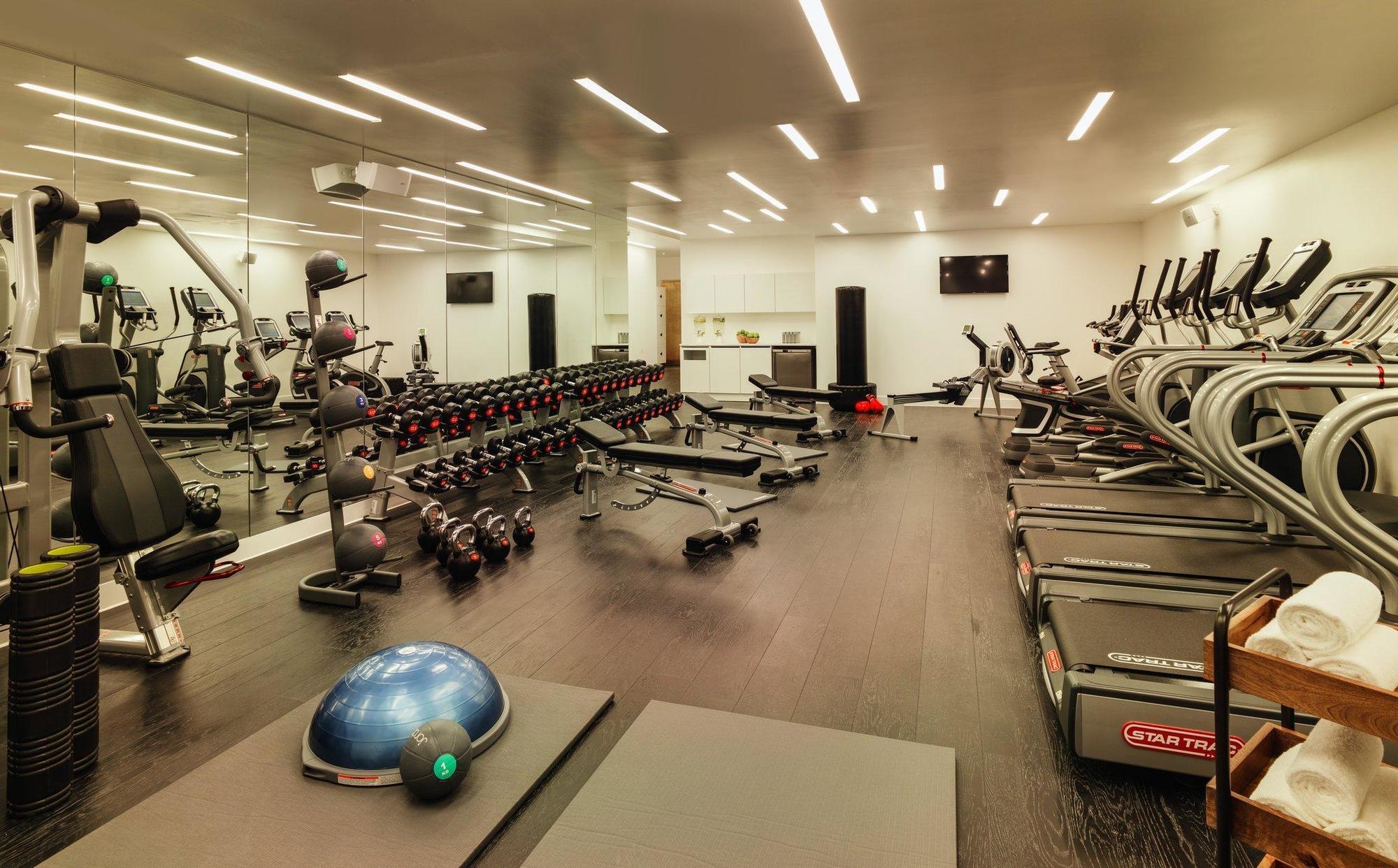 Hotel Sea Containers Londra Esterno foto The photo shows a modern gym space. On one side, there are several pieces of cardio equipment, including elliptical machines and treadmills. Along another wall, there is a set of free weights arranged on a rack, indicating a focus on strength trainin