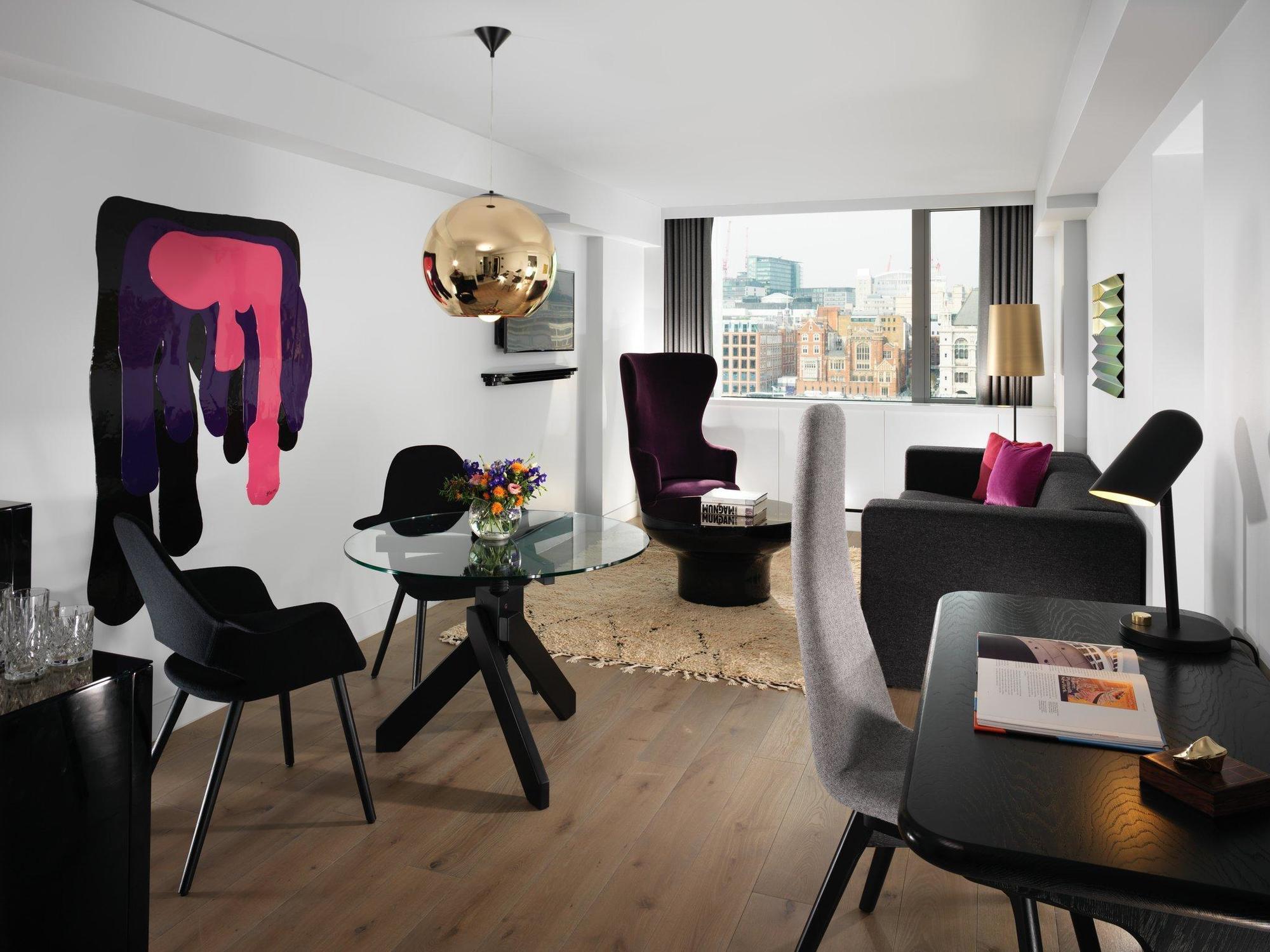Hotel Sea Containers Londra Esterno foto The photo shows a modern and stylish living space. It features a light-colored wooden floor and a layout that includes a glass dining table surrounded by black chairs. There’s a lounge area with a couple of armchairs, one of which has a playful and u