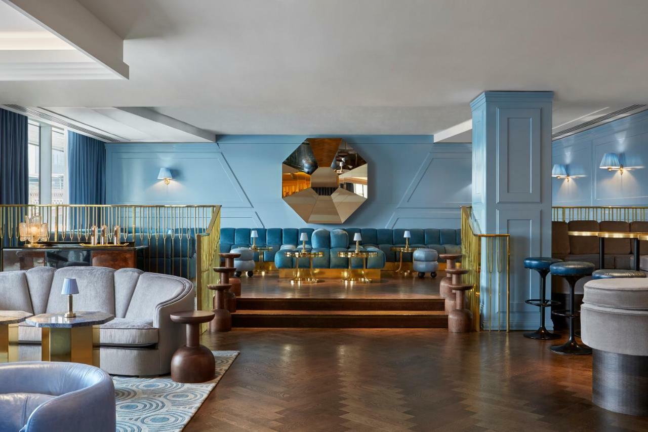 Hotel Sea Containers Londra Esterno foto The photo shows a stylish and modern interior of a lounge or bar. The space features soft blue walls and various seating options, including plush armchairs and small tables. There is a prominent mirror that's octagonal in shape, adding a decorative e