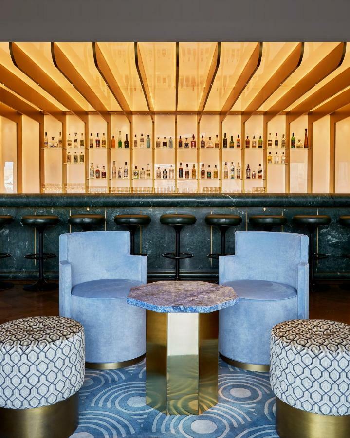 Hotel Sea Containers Londra Esterno foto The photo showcases a modern bar interior. In the background, there is a long bar counter with various bottles displayed on shelves illuminated by soft lighting. The bar stools are sleek and black, positioned in front of the counter. In the foregroun